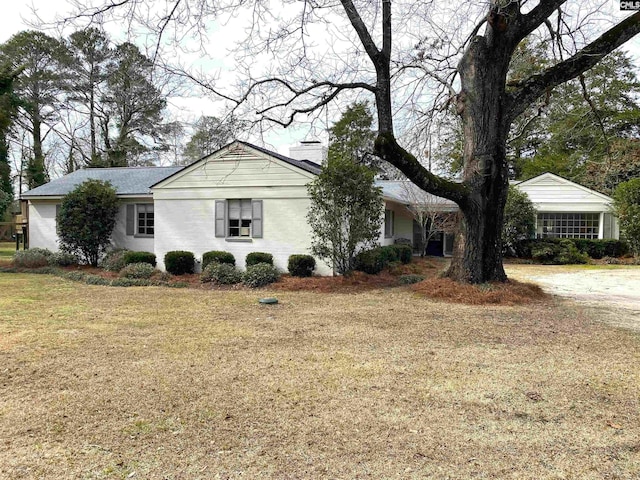 ranch-style home featuring a front lawn and a chimney