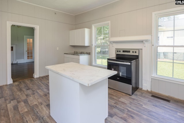 kitchen featuring visible vents, ornamental molding, stainless steel range with electric cooktop, white cabinetry, and wood finished floors