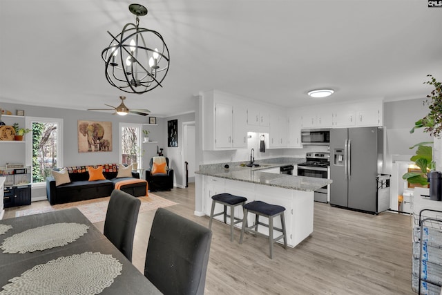 interior space with stainless steel appliances, white cabinetry, a sink, and a peninsula