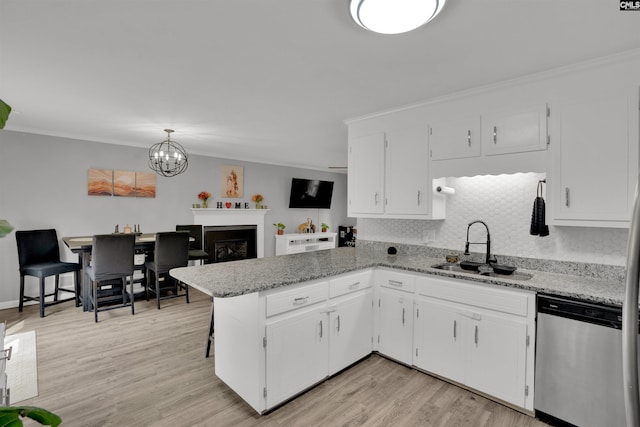 kitchen with a peninsula, light wood-type flooring, stainless steel dishwasher, white cabinetry, and a sink