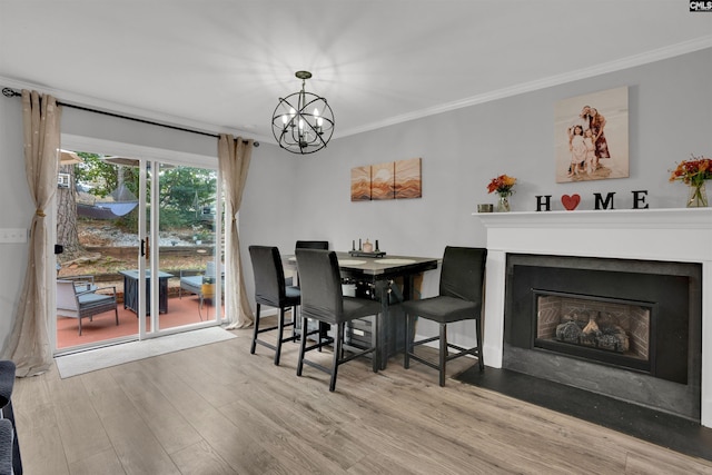 dining room with a fireplace with flush hearth, a notable chandelier, crown molding, and wood finished floors