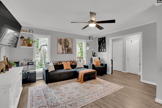 living room with light wood finished floors, ornamental molding, plenty of natural light, and baseboards