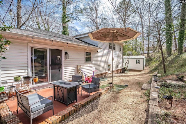 exterior space with central AC unit, a fire pit, an outdoor structure, a shed, and a patio area