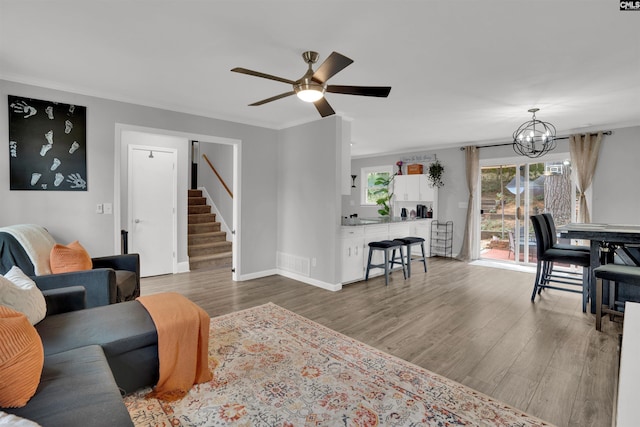 living room with ornamental molding, visible vents, stairway, and wood finished floors