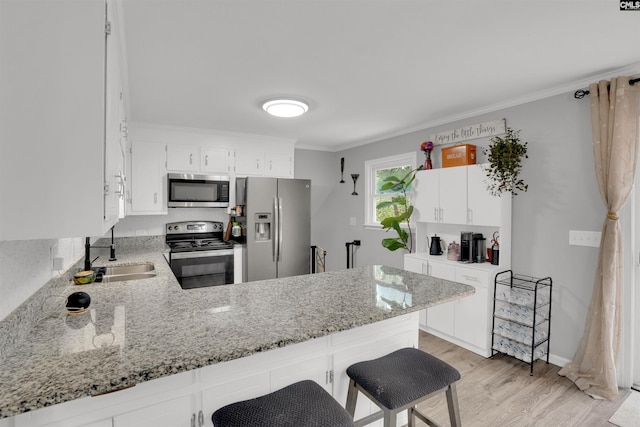 kitchen with ornamental molding, a peninsula, appliances with stainless steel finishes, and a sink