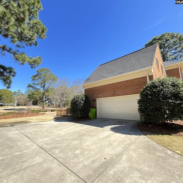 view of home's exterior featuring concrete driveway, brick siding, and a shingled roof