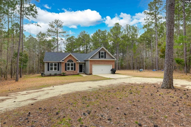 view of front facade featuring a garage, driveway, brick siding, and a forest view