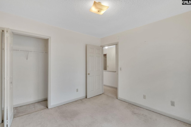 unfurnished bedroom with a textured ceiling, a closet, carpet, and baseboards