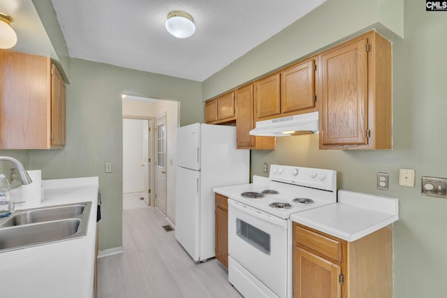 kitchen with a textured ceiling, under cabinet range hood, white appliances, a sink, and light countertops