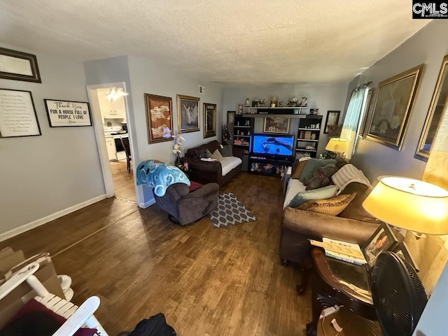 living area featuring a textured ceiling, wood finished floors, and baseboards