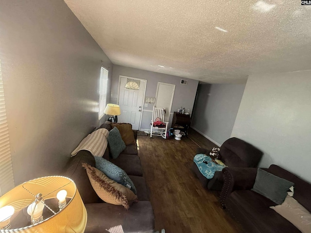 living area featuring wood finished floors, a textured ceiling, baseboards, and visible vents