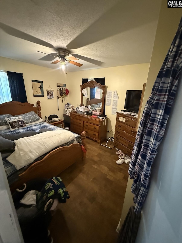 bedroom with ceiling fan, a textured ceiling, and wood finished floors