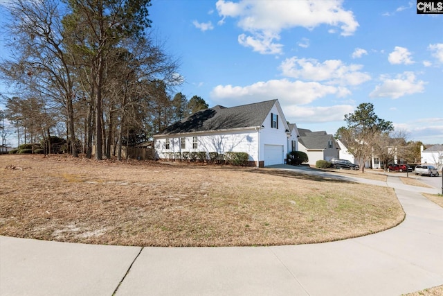 view of property exterior with an attached garage, a residential view, concrete driveway, and a yard