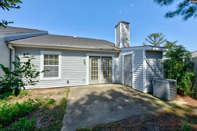 rear view of property featuring cooling unit, a patio, a chimney, and an outbuilding