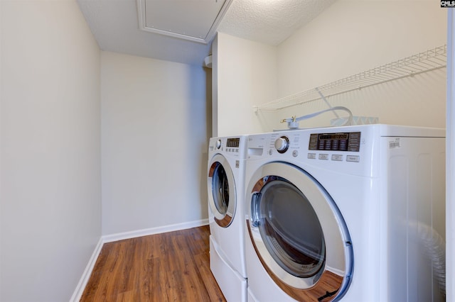 laundry area featuring a textured ceiling, laundry area, wood finished floors, baseboards, and washer and clothes dryer