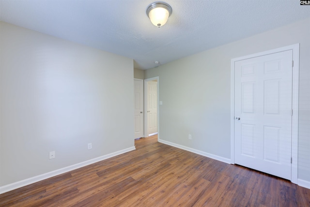 unfurnished bedroom featuring a textured ceiling, wood finished floors, and baseboards