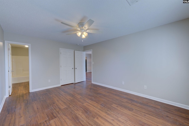 unfurnished bedroom with ceiling fan, baseboards, dark wood-style flooring, and ensuite bathroom