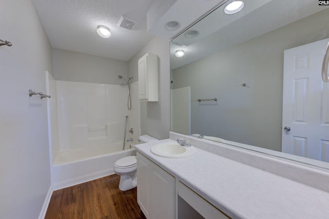 full bathroom with a textured ceiling, toilet, wood finished floors, vanity, and visible vents