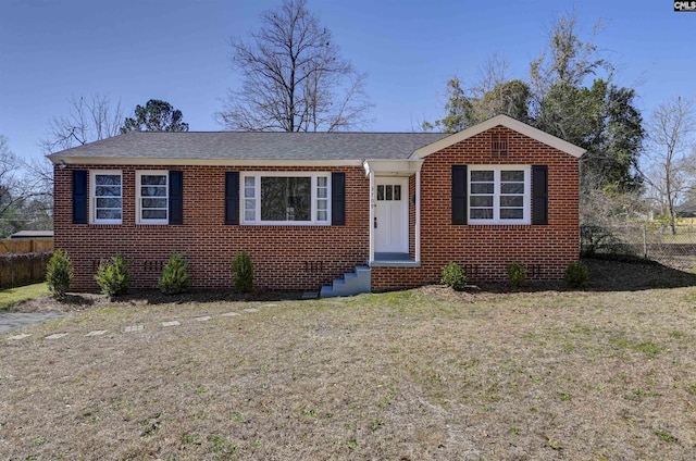 view of front facade featuring entry steps, a front yard, fence, and brick siding