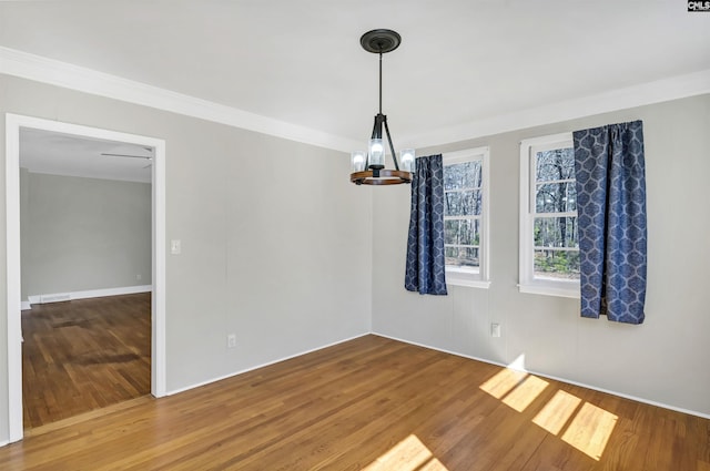 unfurnished room with a notable chandelier, crown molding, and wood finished floors