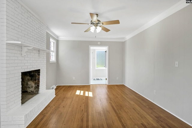 unfurnished living room featuring ornamental molding, a brick fireplace, wood finished floors, and a ceiling fan