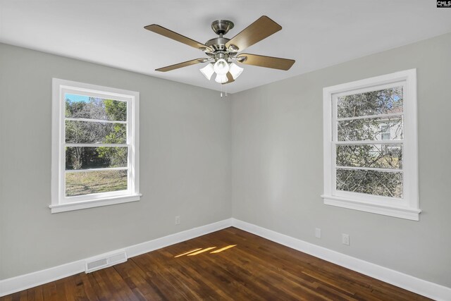 unfurnished room featuring dark wood-type flooring, a ceiling fan, visible vents, and baseboards