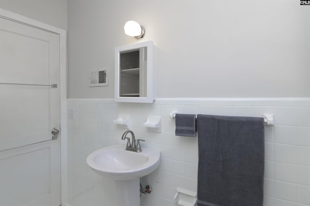 bathroom featuring a wainscoted wall, a sink, and tile walls