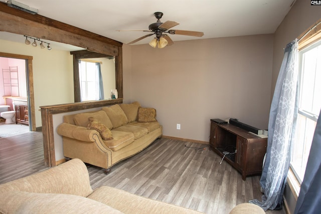 living area featuring ceiling fan, track lighting, baseboards, and wood finished floors