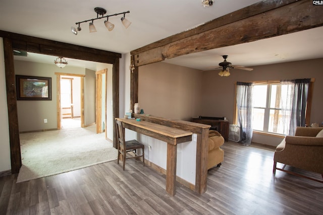 unfurnished living room featuring baseboards, ceiling fan, beamed ceiling, wood finished floors, and track lighting