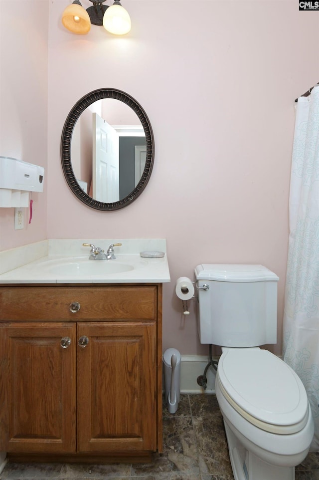 bathroom with baseboards, vanity, and toilet