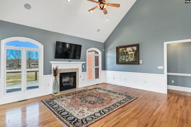 living room with ceiling fan, a wainscoted wall, a premium fireplace, wood finished floors, and visible vents