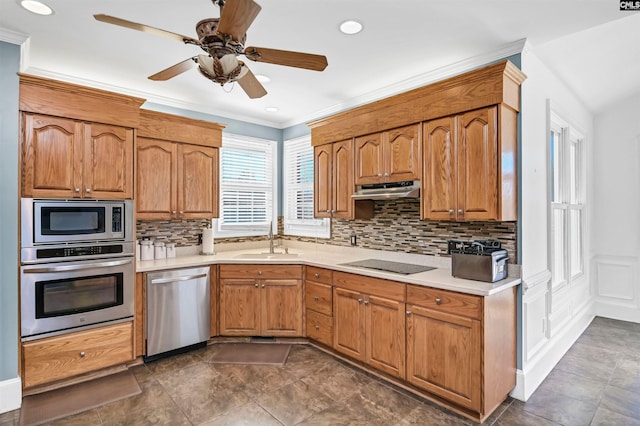 kitchen with appliances with stainless steel finishes, light countertops, a sink, and crown molding