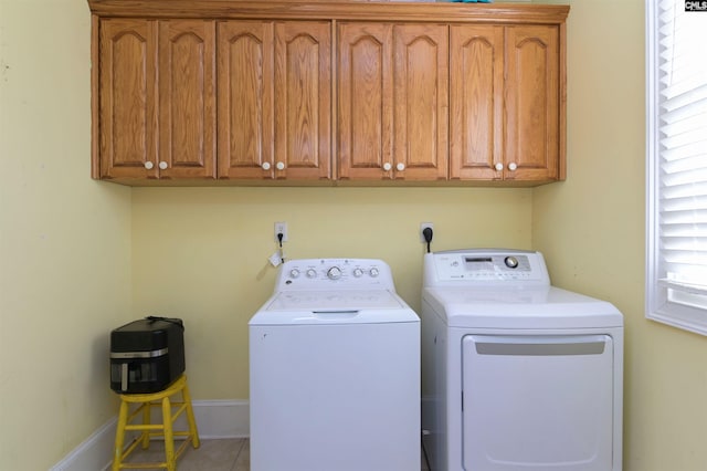 clothes washing area featuring cabinet space, tile patterned flooring, baseboards, and washing machine and clothes dryer