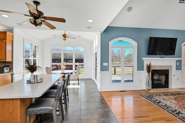 interior space featuring vaulted ceiling, light countertops, a wealth of natural light, and wainscoting