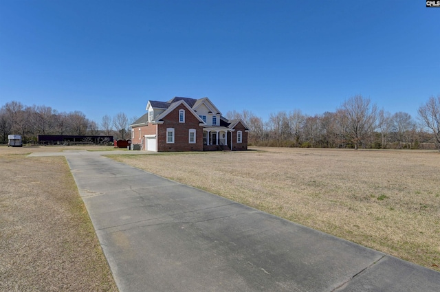 exterior space featuring a garage, a yard, brick siding, and concrete driveway