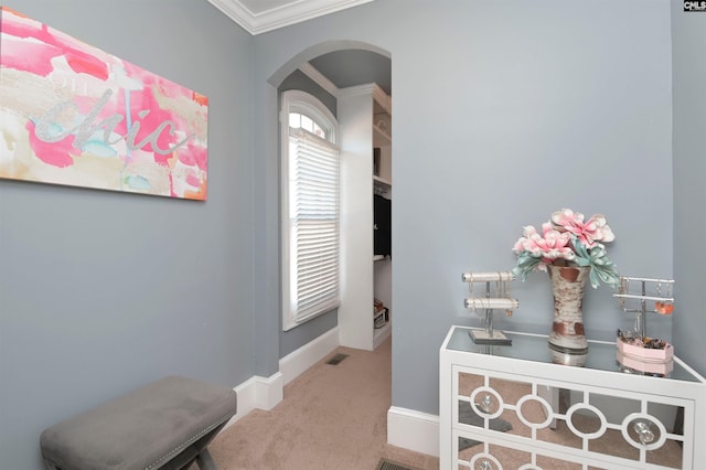 hallway with arched walkways, carpet flooring, visible vents, baseboards, and ornamental molding