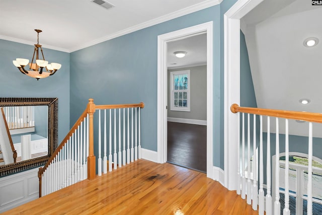 hall featuring baseboards, ornamental molding, wood finished floors, an upstairs landing, and a notable chandelier