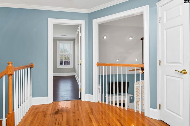 corridor with ornamental molding, wood finished floors, an upstairs landing, and baseboards