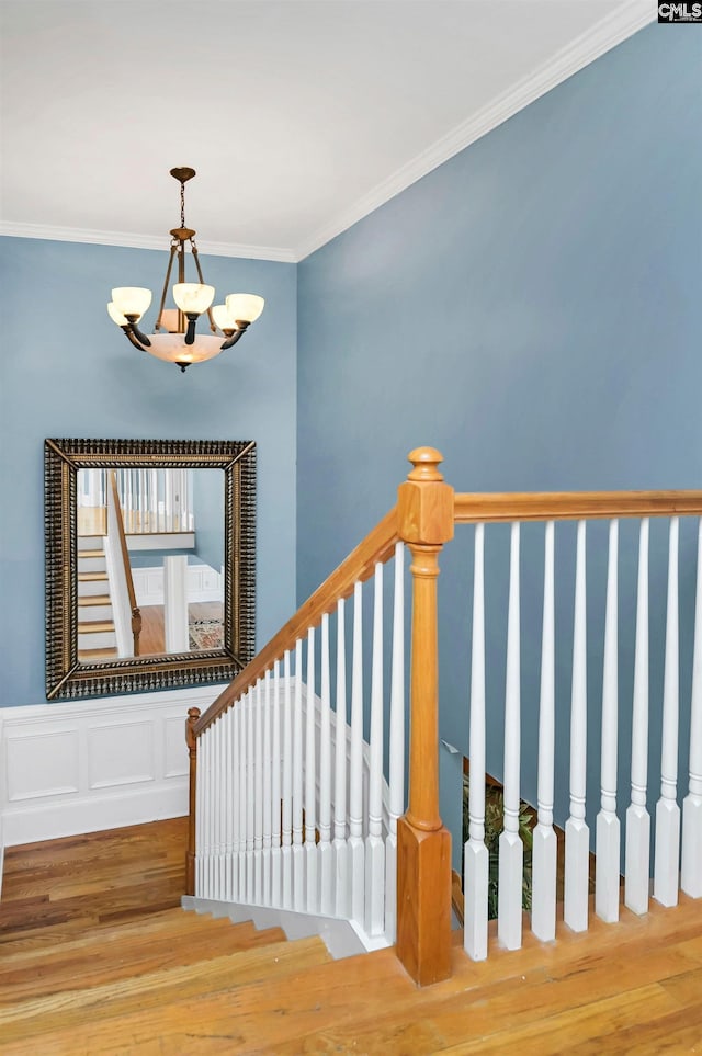 stairs featuring a chandelier, ornamental molding, and wood finished floors