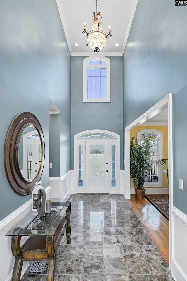 foyer with a chandelier, ornamental molding, and a wealth of natural light