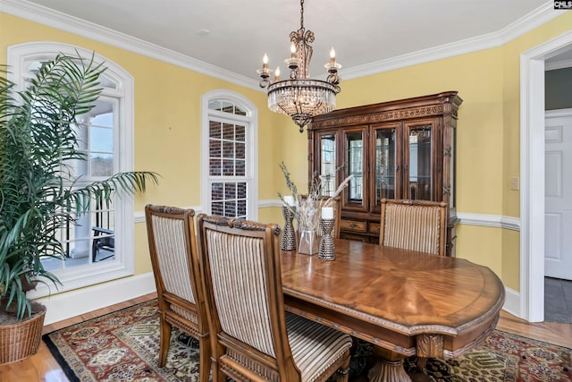 dining space with a notable chandelier, baseboards, ornamental molding, and wood finished floors