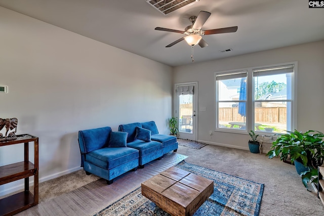 carpeted living area with a ceiling fan, visible vents, and baseboards