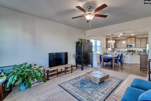 living area featuring ceiling fan with notable chandelier