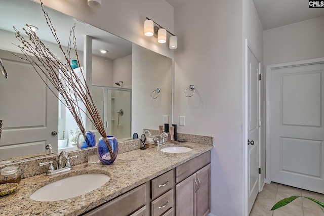 bathroom with double vanity, a stall shower, tile patterned flooring, and a sink