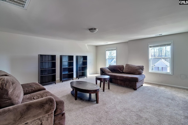 living area featuring visible vents, light carpet, and baseboards