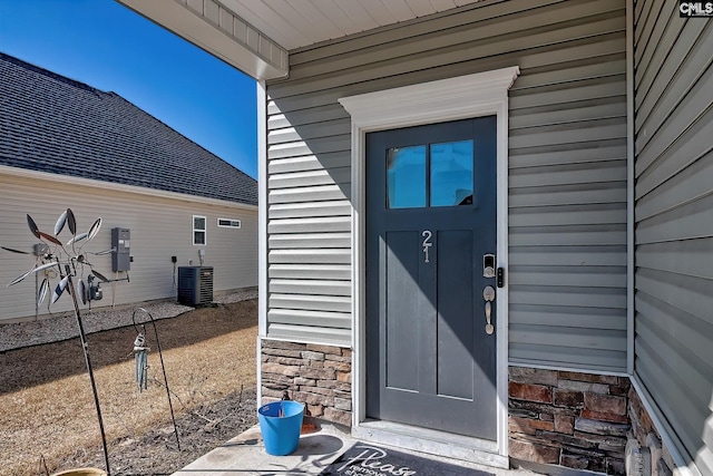 entrance to property featuring stone siding and central AC unit