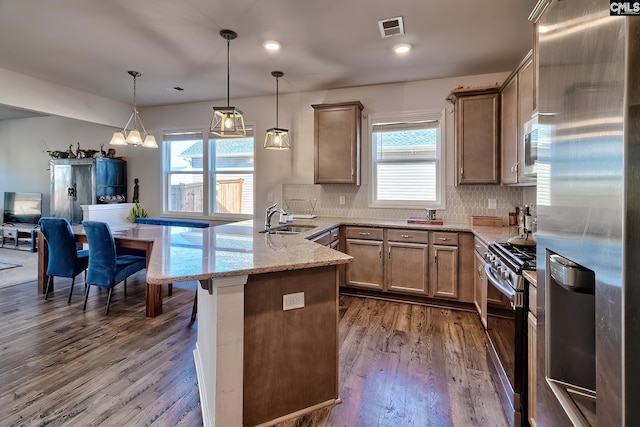 kitchen featuring a peninsula, a sink, visible vents, appliances with stainless steel finishes, and dark wood finished floors