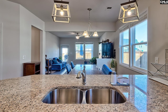 kitchen featuring pendant lighting, a sink, visible vents, and light stone countertops