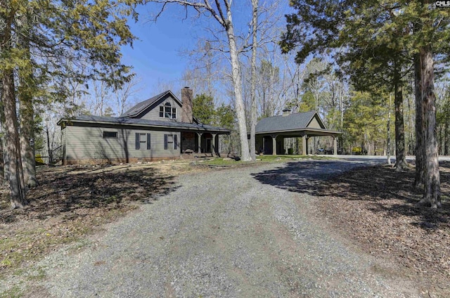 view of front facade with driveway, a carport, and a chimney