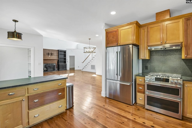 kitchen with tasteful backsplash, dark countertops, hardwood / wood-style floors, stainless steel appliances, and under cabinet range hood